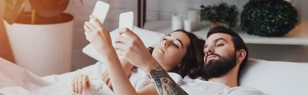 Yatakta Yatan Akıllı Telefonlar Kullanarak Güzel Genç Çift — Stok fotoğraf