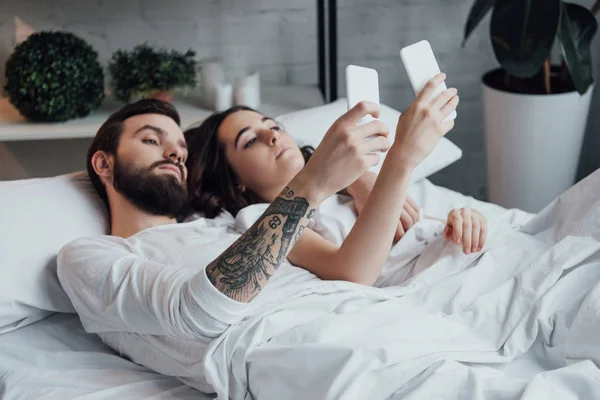 Mooie Jonge Paar Liggend Bed Het Gebruik Van Smartphones — Stockfoto