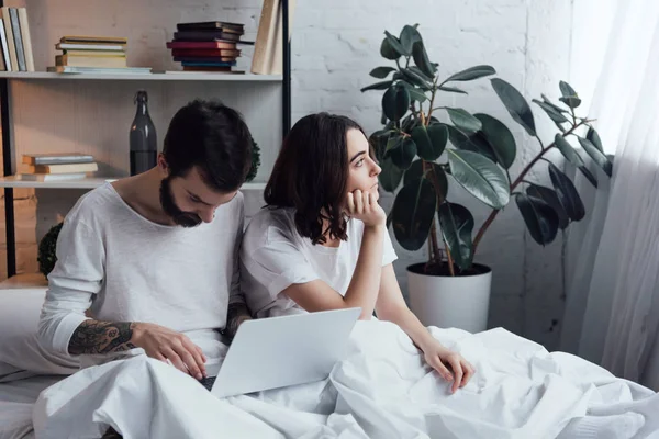 Barbudo Homem Deitado Cama Usando Laptop Enquanto Entediado Mulher Propping — Fotografia de Stock