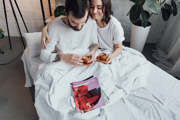 Beautiful Young Couple Lying Bed Coffee Cups Hugging Morning — Stock Photo, Image