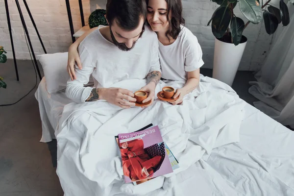 Hermosa Pareja Joven Acostada Cama Con Tazas Café Abrazos Mañana — Foto de Stock