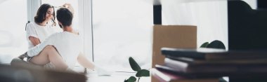 güzel genç çiftin sarılma ve kopya alanı ile pencere pervazına evde oturan seçici odak