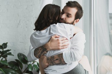 beautiful young couple passionately hugging at home