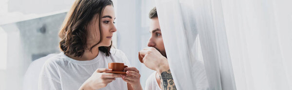 beautiful young couple drinking coffee in morning and looking at each other