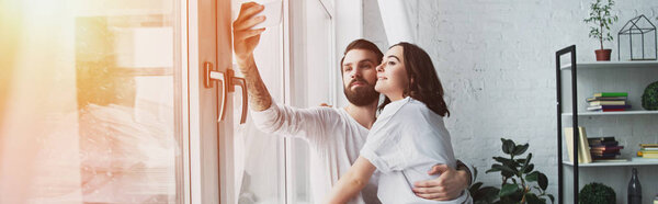 красивая молодая пара делает селфи на смартфоне дома с копировальным пространством и солнечным светом
