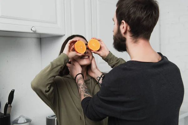 Man Omhelst Vrouw Houdt Van Sinaasappelen Voor Gezicht Keuken — Stockfoto