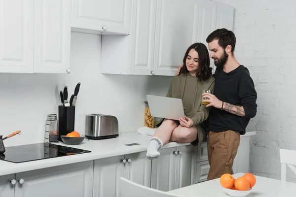 Hombre Guapo Beber Jugo Mientras Que Mujer Usando Ordenador Portátil — Foto de Stock