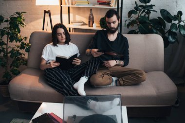 güzel kadın vinil kayıt tutarak ve oturma odasında müzik adam kitap okuma