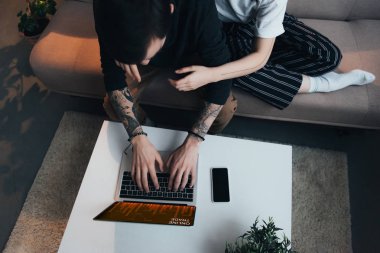 Çift oturma ang evde online ticaret Web sitesi ile dizüstü bilgisayar kullanırken sarılma görünümünü kırpılmış 