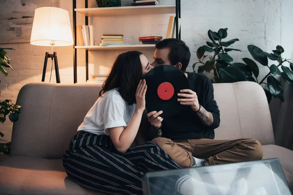 Beautiful Young Couple Covering Faces Vinyl Record Kissing While Sitting — Stock Photo, Image