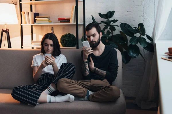 Pareja Joven Enfocada Sentado Sofá Uso Teléfonos Inteligentes Sala Estar — Foto de Stock