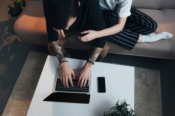 裁剪视图的夫妇坐在和拥抱 而使用笔记本电脑与空白屏幕在家里 — 图库照片