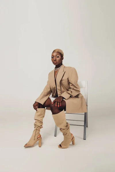 Fashion Shoot African American Woman Beige Jacket Sitting Chair Grey — Stock Photo, Image