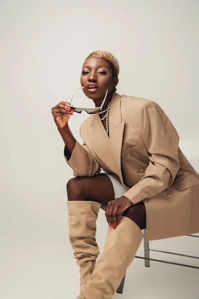 Fashionable African American Girl Sunglasses Beige Jacket Sitting Chair Grey — Stock Photo, Image