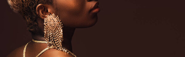 cropped view of african american woman in fashionable earrings isolated on brown