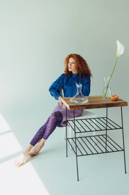 gri üzerinde Calla çiçek ve vazolar ile masada poz güzel trendy Redhead kız