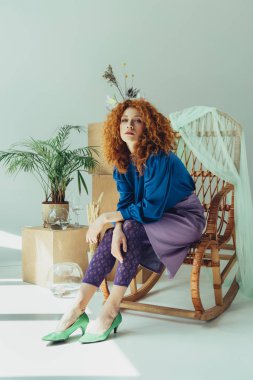 ahşap kutular ve kurutulmuş çiçekler yakın hasır sandalyede oturan şık Redhead kız gri