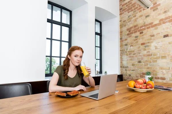 Mulher Bebendo Suco Laranja Perto Torradas Gadgets Mesa — Fotografia de Stock