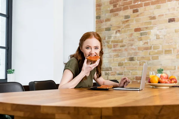 Selective Focus Woman Looking Camera While Eating Toast Laptop Table — Stock Photo, Image