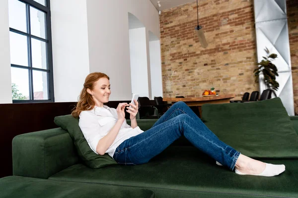 Vista Lateral Mulher Atraente Sorrindo Usar Smartphone Sofá — Fotografia de Stock