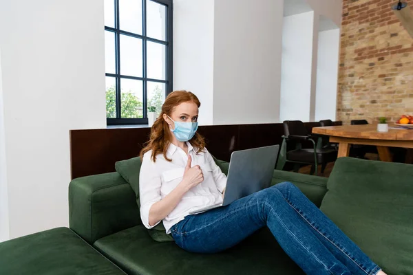Red Haired Woman Medical Mask Showing Thumb While Using Laptop — Stock Photo, Image
