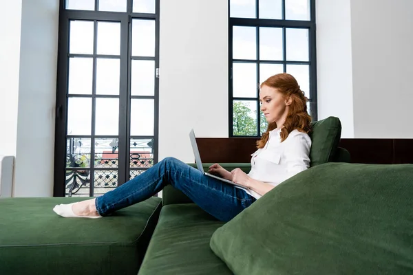 Vista Lateral Freelancer Cabelos Vermelhos Usando Laptop Sofá — Fotografia de Stock