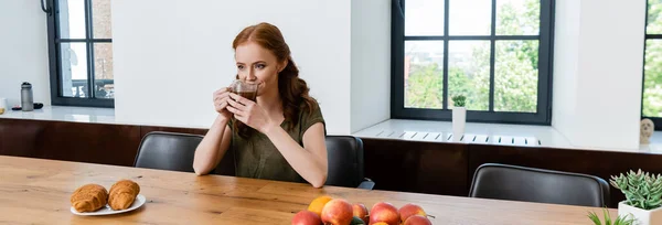 全景拍摄的女人在桌面上的羊角面包附近喝咖啡 — 图库照片