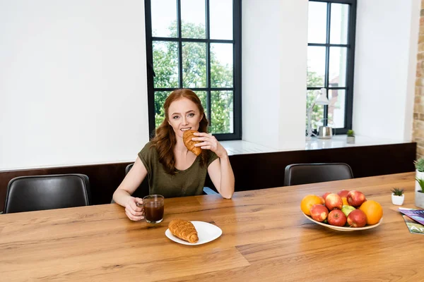 Red Haired Woman Eating Croissant Holding Cup Coffee Home — Stock Photo, Image