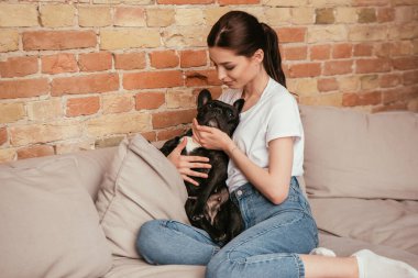 Güzel bir kadın dokunuyor ve siyah Fransız bulldog 'una bakıyor. 