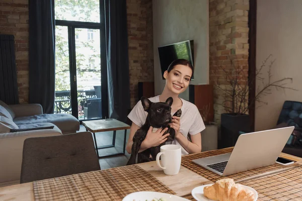Cheerful Freelancer Holding Arms Cute French Bulldog Looking Camera Laptop — Stock Photo, Image