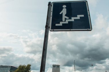Arka planda bulutlu gökyüzü olan şehir caddesinde alçak açılı merdiven işareti 