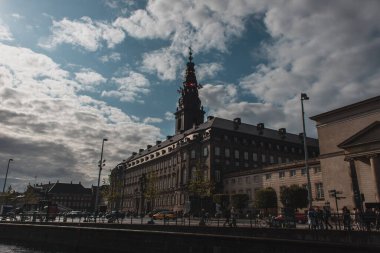 COPENHAGEN, DENMARK - 30 Nisan 2020: Christiansborg Sarayı kulesi ve arka planda bulutlu gökyüzü ile Urban Caddesi 