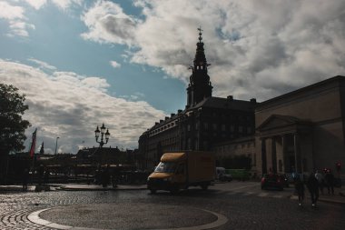 COPENHAGEN, DENMARK - 30 Nisan 2020: Sokakta Christiansborg Sarayı ile yürüyen insanlar ve arka planda bulutlu gökyüzü 