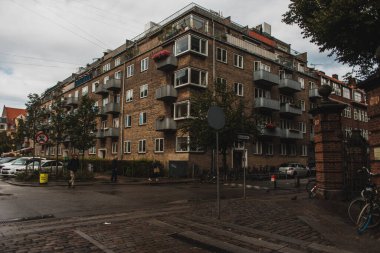 COPENHAGEN, DENMARK - 30 Nisan 2020: Yol kenarında arabaları ve arka planda bulutlu gökyüzü olan şehir caddesi 