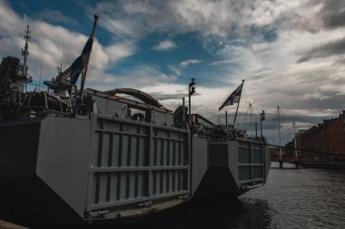 COPENHAGEN, DENMARK - 30 Nisan 2020: Arka planda bulutlu gökyüzü olan kanal suyunda bayraklı gemi 