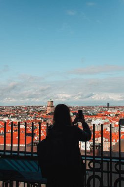 Kopenhag, Danimarka 'da turistlerin binalar ve bulutlu gökyüzü ile akıllı telefonlardan fotoğraf çekerken arka plan görüntüsü 