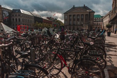 COPENHAGEN, DENMARK - 30 Nisan 2020: Arka planda binalar ve bulutlu gökyüzü ile kentsel caddede bisikletlerin seçici odak noktası 