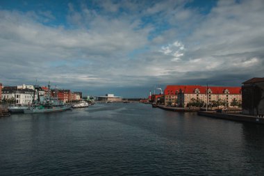 Kanal yakınındaki binalar ve limandaki tekneler Kopenhag, Danimarka 'da arka planda bulutlu gökyüzü 