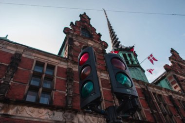 Selective focus of traffic lights with facade of Borsen building and blue sky at background in Copenhagen, Denmark  clipart