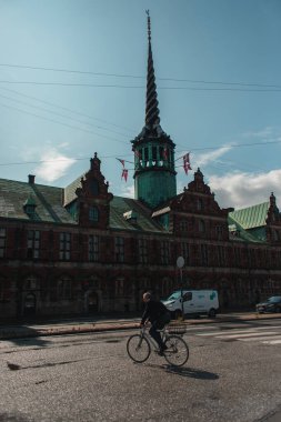 COPENHAGEN, DENMARK - 30 Nisan 2020: Borsen 'in dış cephesinde bisiklet süren adam 