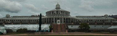 Panoramic orientation of facade of University of Botanical Garden with cloudy sky at background in Copenhagen, Denmark  clipart