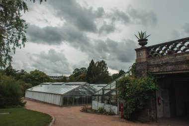 Greenhouses and botanical garden with cloudy sky at background in Copenhagen, Denmark  clipart