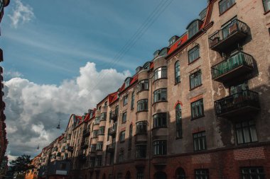 Arka planda güneş ışığı ve bulutlu gökyüzü olan eski binanın ön cephesi, Kopenhag, Danimarka 