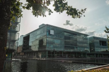 Kanal yakınında, arka planda bulutlu gökyüzü, Kopenhag, Danimarka olan bir binanın seçmeli cam cephesi 
