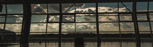 Panoramic orientation of windows in airport waiting hall with cloudy sky at background in Copenhagen, Denmark 