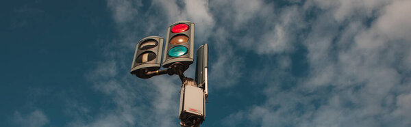 Panoramic shot of traffic lights with cloudy sky at background 