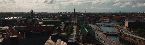 Panoramic crop of roofs of buildings and canal with cloudy sky at background in Copenhagen, Denmark 