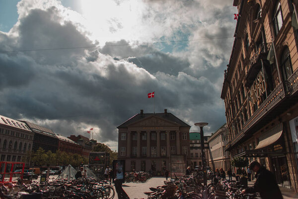 КОПЕНГАГЕН, ДЕНМАРК - 30 апреля 2020 года: Велосипеды на городской площади со зданиями и облачным небом на заднем плане
 