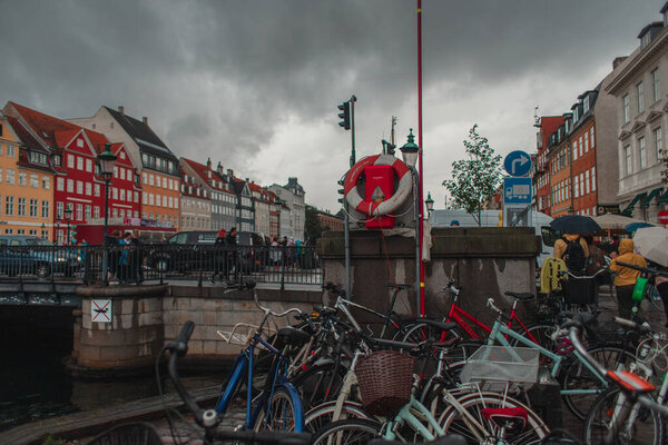 COPENHAGEN, DENMARK - APRIL 30, 2020: Bicycles near canal on Nyhavn Harbor with cloudy sky at background 