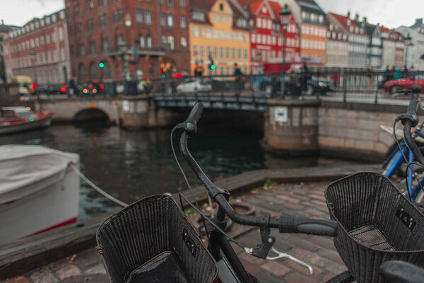 Selective focus of bicycles on promenade near canal on Nyhavn Harbor, Copenhagen, Denmark 